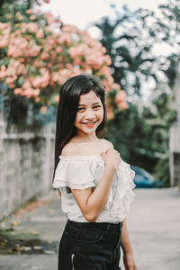 Portrait of smiling girl standing against tree