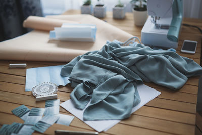 Work process - sewing machine and patterns on the table in workshop, blue cloth on a wooden table 