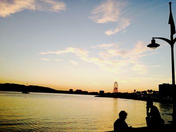 Silhouette people in water at sunset