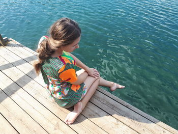 High angle view of girl sitting on pier over lake