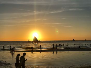 Silhouette people at beach against sky during sunset