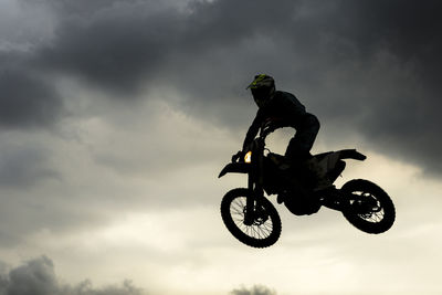Low angle view of man performing stunt with motorcycle against sky