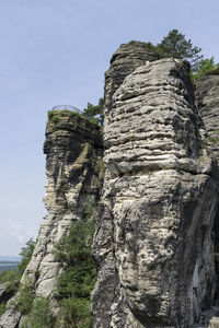 Low angle view of sculpture on cliff against sky