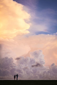 People standing on land against sky during sunset