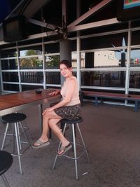Full length of woman sitting on stool in cafe