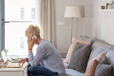 Woman using laptop on couch at home