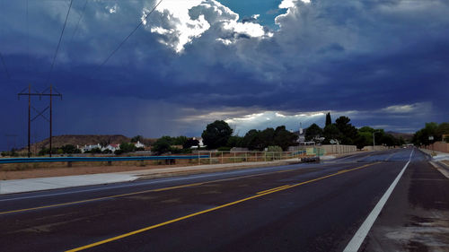 Road by trees against sky
