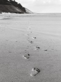 High angle view of footprints at beach against sky