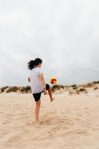 Woman playing with ball on beach