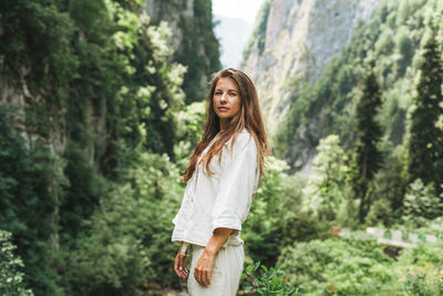 Young woman traveler with long blonde hair looks at beautiful view of mountains