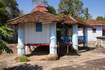 House amidst trees and houses on field against sky