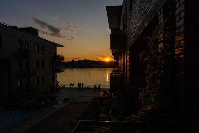 Buildings by sea against sky during sunset