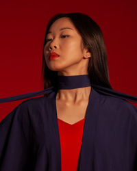 Portrait of young woman standing against yellow background