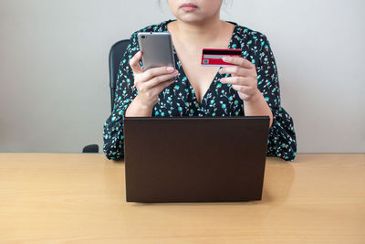 Midsection of woman using smart phone on table