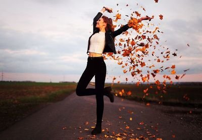 Woman standing by road against sky during sunset