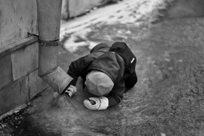 Boy looking at water flowing from pipe