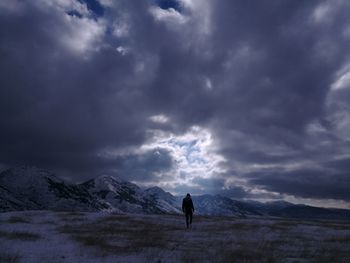 Silhouette man standing on snow covered landscape against sky