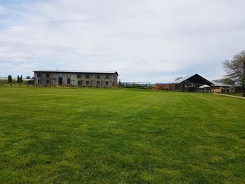 House on grassy field against sky