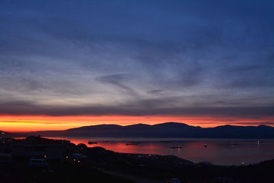 Scenic view of silhouette mountains by sea against sky during sunset