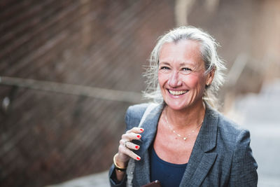 Portrait of happy mature businesswoman standing outdoors