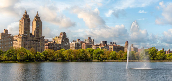 Buildings by lake against sky