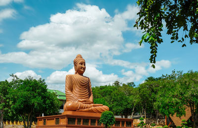 Statue against trees and plants against sky