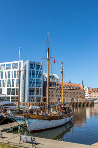 Sailboats moored at harbor against clear blue sky