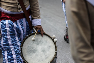 Midsection of man with drum on street in city
