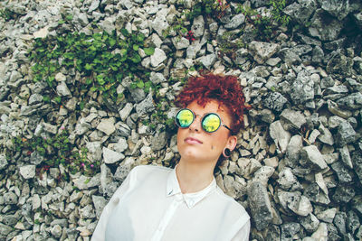 Woman in sunglasses standing against wall