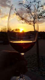 Close-up of beer glass against sunset