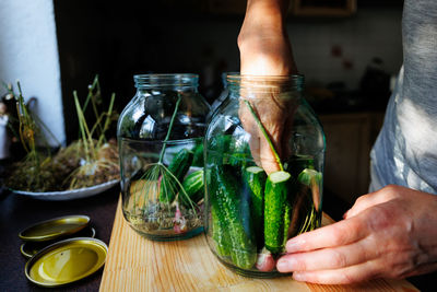 Cropped hand of woman holding drink on table