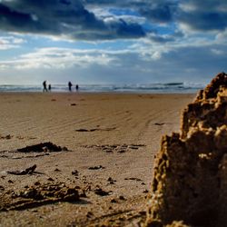 Scenic view of beach against cloudy sky