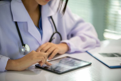 Midsection of man using mobile phone on table