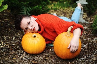 Portrait of woman lying with pumpkins on field