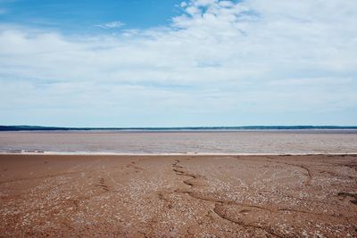 Scenic view of beach against cloudy sky