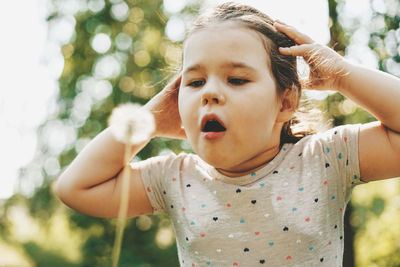 Close-up of cute girl blowing dandelion seed