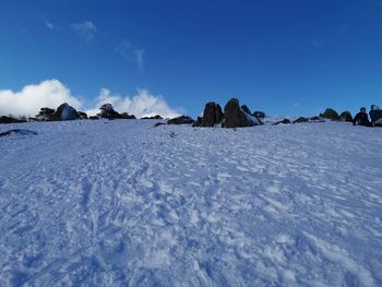 Snow covered landscape against blue sky