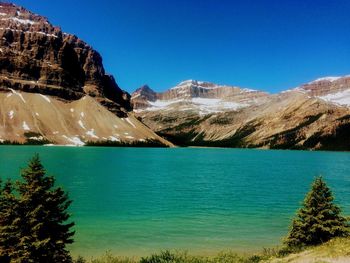 Scenic view of lake and mountains against clear blue sky