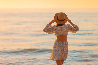 Rear view of woman standing at beach