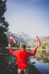 Rear view of man standing in red flag against sky