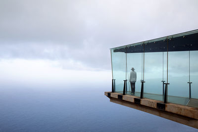 Man standing on skywalk in front of sky