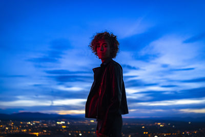 Portrait of young woman standing against sky during sunset