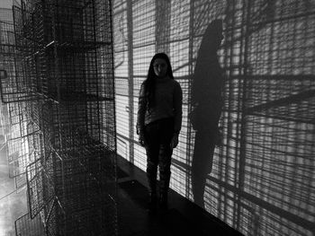 Portrait of young woman standing against wall