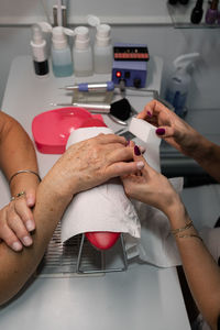 Senior woman in cosmetic salon doing manicure with specialist