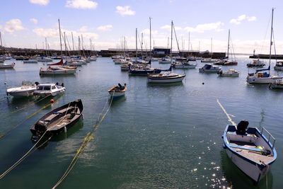 Boats moored at harbor against sky