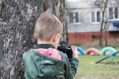 Kid on the street in a jacket with an film camera