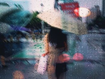 Woman seen through wet glass window in rainy season