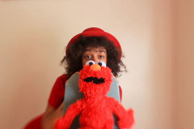 Portrait of woman holding toy against wall