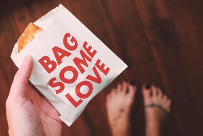 Cropped hand of woman holding food with text on wrapper