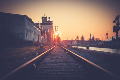 Surface level of railroad tracks against clear sky during sunset